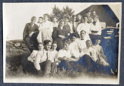 Photograph of a group of people seated on and by a stone wall