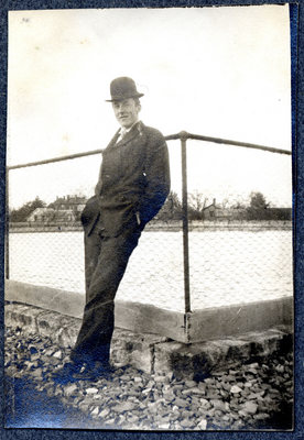 Photograph of a man leaning against a fence