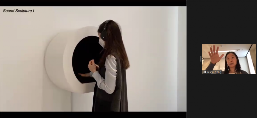 A woman with headphones is sticking her sand into one of Song's invisible sound sculptures.